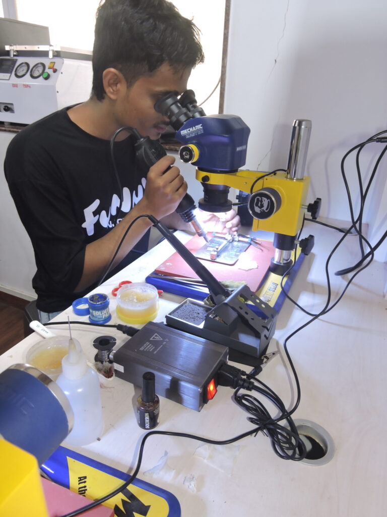 Student confidently practicing integrated circuit replacement in a training lab.